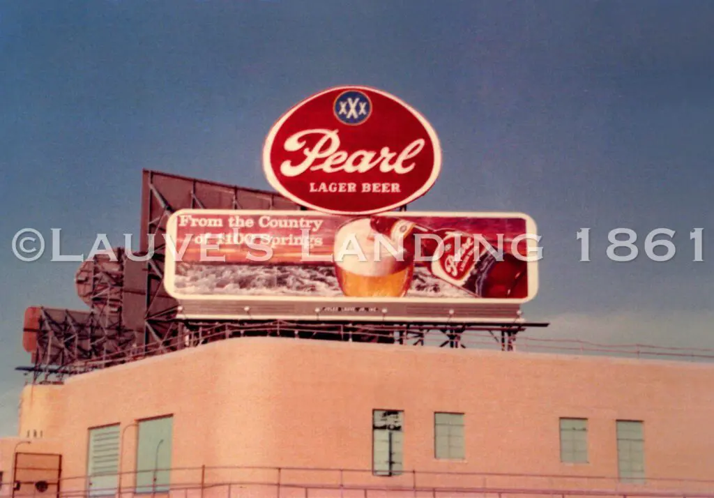 A heritage billboard advertising pearl cola on top of a building.
